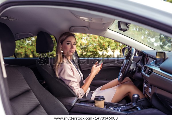Beautiful girl business lady driving car, summer in\
city, meets passenger, trip to work, long hair casual makeup. In\
hand mobile phone, meeting loved one, transporting passenger, date,\
open car door