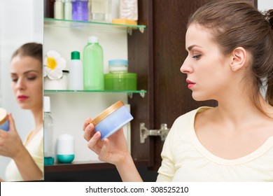 Beautiful Girl Choosing Beauty Products From The Bathroom Cabinet