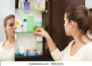 Beautiful Girl Choosing Beauty Products From The Bathroom Cabinet