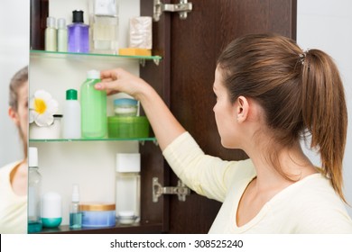 Beautiful Girl Choosing Beauty Products From The Bathroom Cabinet