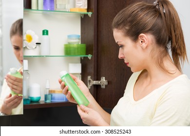 Beautiful Girl Choosing Beauty Products From The Bathroom Cabinet