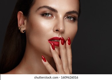 Beautiful girl with a classic make up and multi-colored nails. Manicure design. Beauty face. Photo taken in the studio