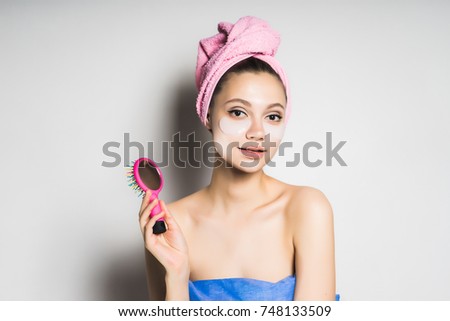beautiful girl with clean skin and with a pink towel on her head holds a comb