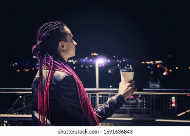 beautiful girl with coffee at night smiling against the background of garlands and city lights. coffee to go.