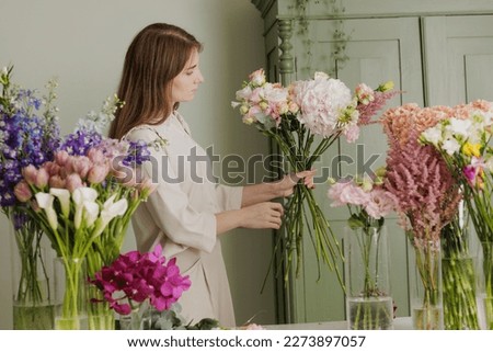 Similar – Woman arranges flower bouquet with roses in vase