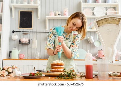 Beautiful girl cooks in the kitchen pie with strawberries