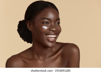 Beautiful Girl With Cosmetic Cream On Face. Smiling Young Woman With Perfect Skin. Concept Of Face Skin Care. Isolated On Beige Background. Studio Shoot