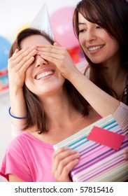 Beautiful girl covering her friend's eyes and giving her a brithday present