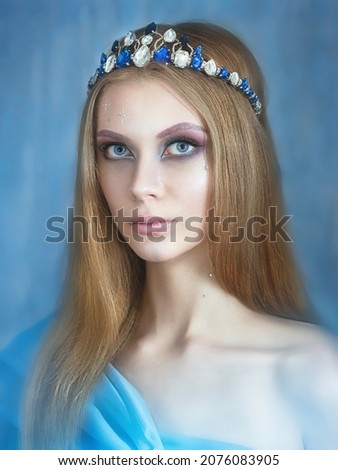 beautiful girl in a crown of stones. With New Year's decorations. On a blue background. Portrait