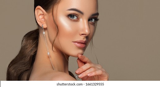 Beautiful girl with  curled tail on her  head . Fashionable and stylish woman in trendy jewelry big earrings rings  .  Fashion look  , beauty and style. Natural makeup & easy styling