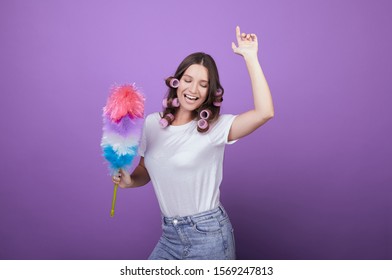 Beautiful girl in curlers and a white T-shirt sings songs and dances while cleaning. Housewife. Cleang. Maid. Cleanliness and cleaning. Homemade routine. House cleaning. - Shutterstock ID 1569247813