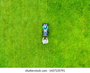 Beautiful Girl Cuts The Lawn. Mowing Lawns. Aerial View Beautiful Woman Lawn Mower On Green Grass. Mower Grass Equipment. Mowing Gardener Care Work Tool. Close Up View. Aerial Lawn Mowing