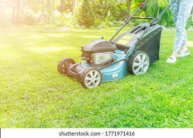 Beautiful Girl Cuts The Lawn. Mowing Lawns. Beautiful Woman Lawn Mower On Green Grass. Mower Grass Equipment. Mowing Gardener Care Work Tool. Close Up View. Lawn Mowing