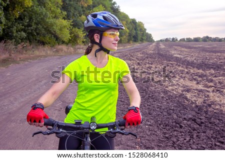 Beautiful girl cyclist with a bicycle on the nature. Healthy lifestyle and sport. Leisure and hobbies
