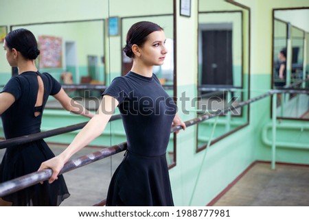 Beautiful girl dancer standing near barre, concentrated look. Ballerina in the dance hall on her scheduled training.