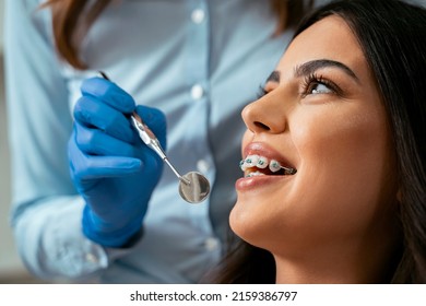 Beautiful Girl With Dental Braces At Dental Checkup, Smiling While Dentist Holding Dental Mirror