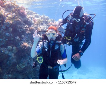 A Beautiful Girl Diver Shows Hands Gesture Signal All Well With A Partner Instructor For Safety Floats Under The Water In The Red Sea With Coral Reefs Egypt, Sharm El-Sheikh, 05/15/2018.