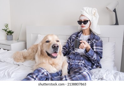 A beautiful girl does spa treatments and has fun with her dog on the bed in the morning. Young woman does a facial and strokes her dog in her bedroom - Powered by Shutterstock