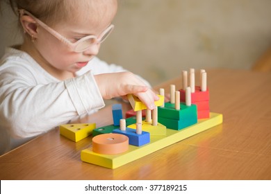 beautiful girl with Down syndrome sorts geometric shapes - Shutterstock ID 377189215