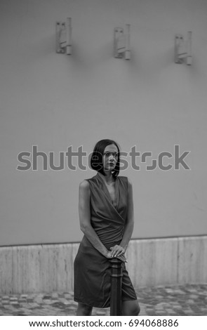 Similar – beautiful brunette short hair girl leaning against  gray rock wall outdoors, wearing black clothes