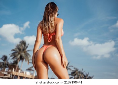 Beautiful girl in a dress and sunglasses posing on the beach, beauty portrait, fashion woman, red lipstick, tanned skin, portrait, sea, sunny island, Bali, hat, cap, jump, up, workout, fitness, ass