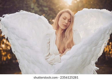 Beautiful girl dressed as an angel in the evening garden