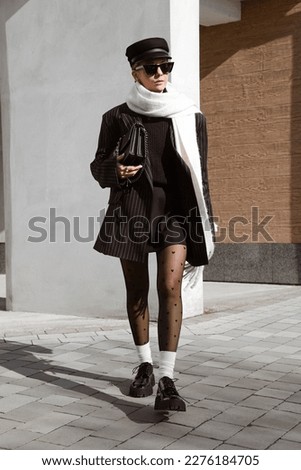 beautiful girl dressed in black striped jacket, white scarf, heart print tights, socks, black patent leather massive shoes, sunglasses, bag, cap, accessories, stylish fashion outfit, lifestyle model