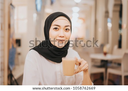 Beautiful girl drinking hot tea with milk,known as Teh Tarik with bokeh background and retro filter effect.