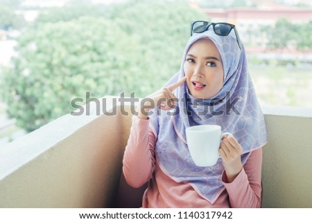 Beautiful girl drinking hot tea with milk known as Teh Tarik