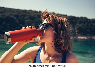 A Beautiful Girl Drinking From A Steel Water Bottle At The Beach