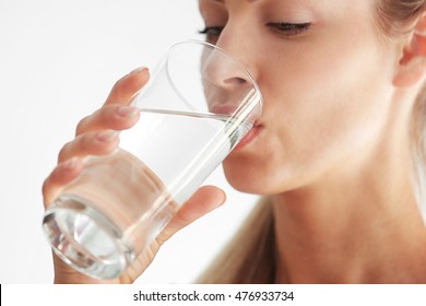 Beautiful girl drinking water on light background - Shutterstock ID 476933734