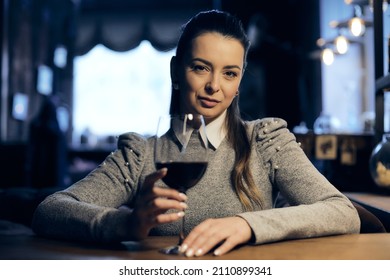 Beautiful girl drinks wine from a glass in a restaurant, a cafe, has a good weekend, a stylish fashionable woman, a brunette young, emotional, outdoor. Close up.