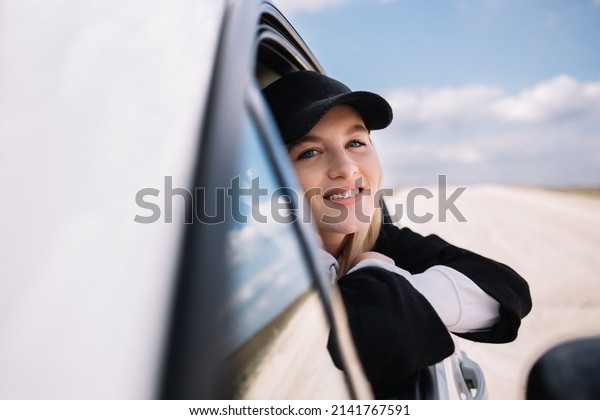 Beautiful girl driving a car, smiling in the side\
mirror of the car
