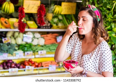 Beautiful Girl Eating Dragon Fruit In A Street Fruit Stand.