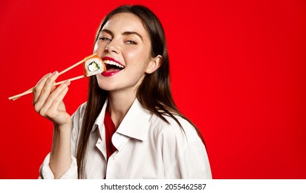 Beautiful girl eating japanese sushi rolls with chopsticks, smiling from satisfaction, order in oriantal fastfood restaurant, delivery concept, red background - Powered by Shutterstock