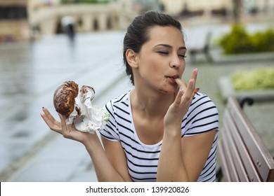 beautiful girl enjoys eating a donut with chocolate and sucking her finger