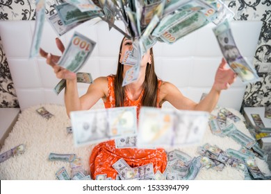 beautiful girl enjoys tremendous wealth. female throws up a lot of banknotes on a white bed, throws money, top view.