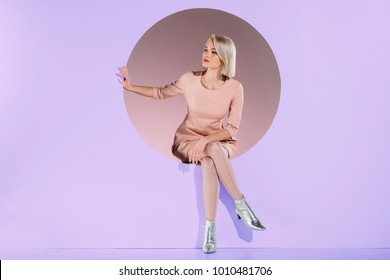 beautiful girl in fashionable clothes sitting on purple