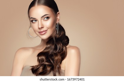 Beautiful girl . Fashionable and stylish woman in trendy jewelry big earrings .Curly ponytail hairstyle. Fashion look , beauty and style. Natural makeup and cosmetics