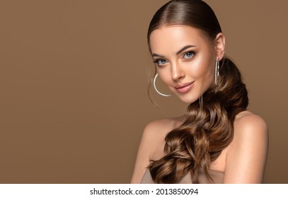 Beautiful girl . Fashionable and stylish woman in trendy jewelry big earrings .Curly ponytail hairstyle.  Fashion look  , beauty and style. Natural makeup and cosmetics