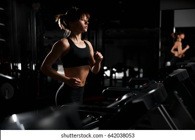 Beautiful girl in a fitness room on the treadmill. Training of the heart.