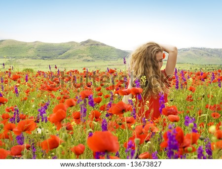beautiful girl with flowers in her hair in a field with poppies and violet flowers