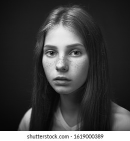 Beautiful girl with freckled skin on her face in studio black and white portrait