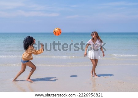 Beautiful girl friendship happy enjoy laughing and play ball the blue sea and white sand beach