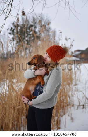 beautiful girl in a fur vest plays with a dog in the snow