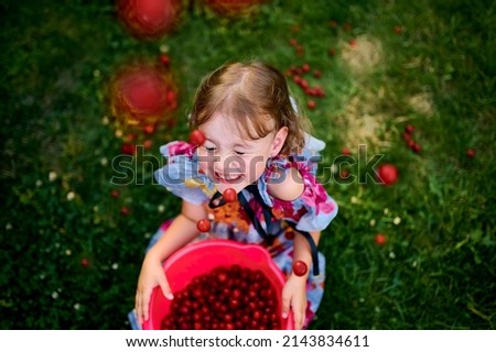 Beautiful girl in the garden. Happy girl with cherries. Girl in the cherry orchard. Cherries. The Cherry Orchard. Beautiful girl tosses berries. Berries. Childhood. Delicious cherries. 