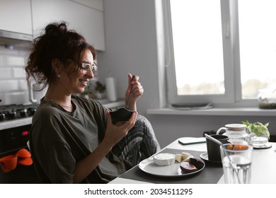 beautiful girl in glasses with curly hair eating breakfast on the kitchen , early morning mood, morning snacks