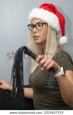 A beautiful girl in a gnome's hat on her head and with a leather whip in her hand.