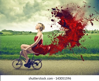 beautiful girl goes by bicycle with red dress