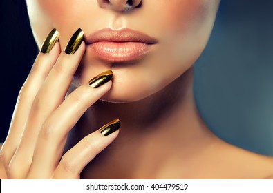 Beautiful girl with the Golden makeup and gold  metal nails.  Fashion woman Portrait